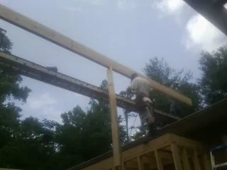 Carpenter setting a ridge beam over a new addition frame — Ice Dam Removal by Roofing Brothers in Afton