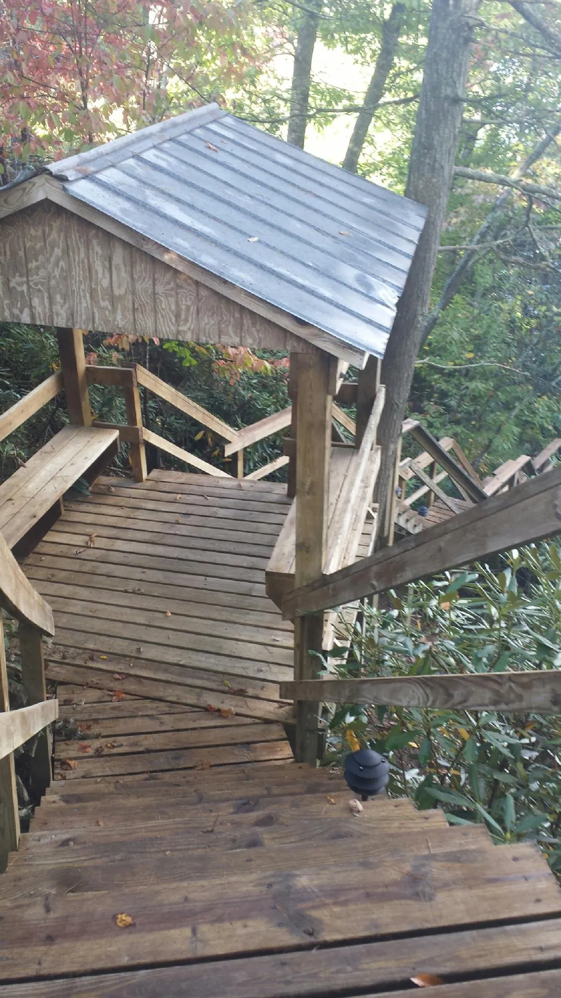 Metal roofed shelter over wooden steps on a wooded walkway — Skylight Repair & Installation work by our crew in Afton